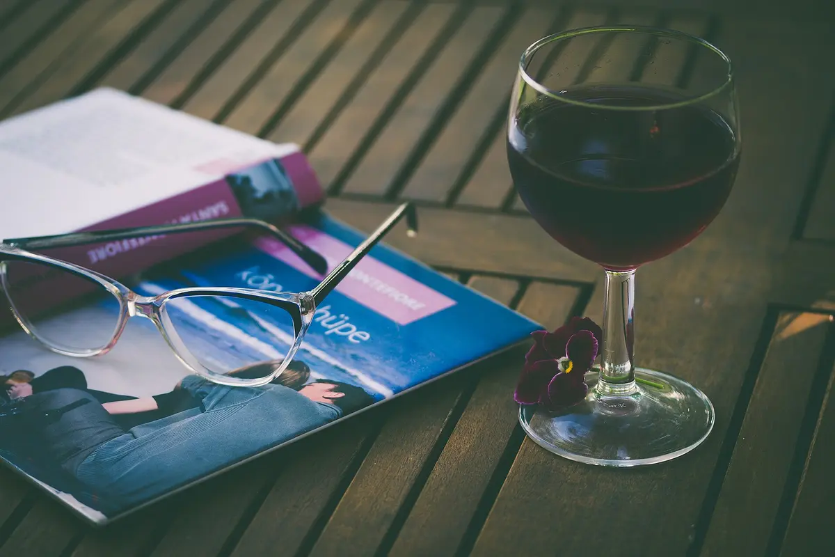 A glass of red wine beside a book