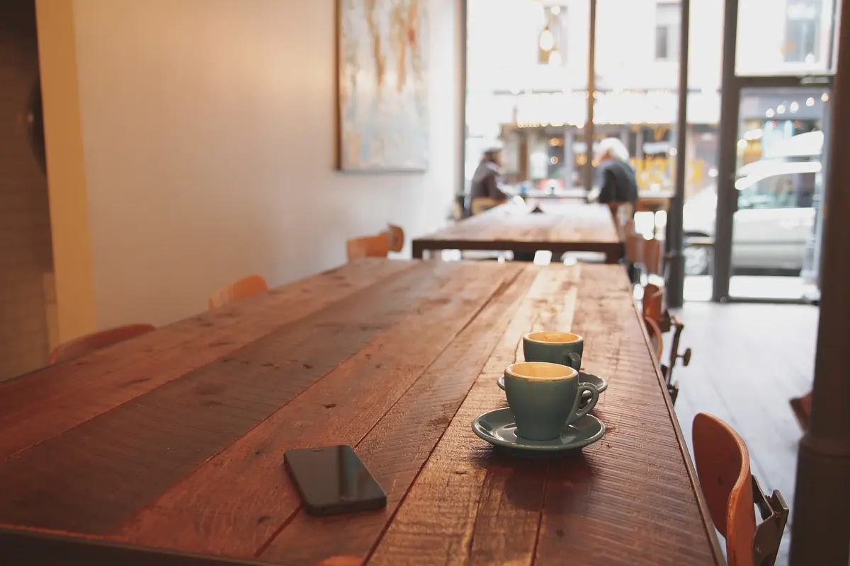 A coffee on a long wooden cafe table