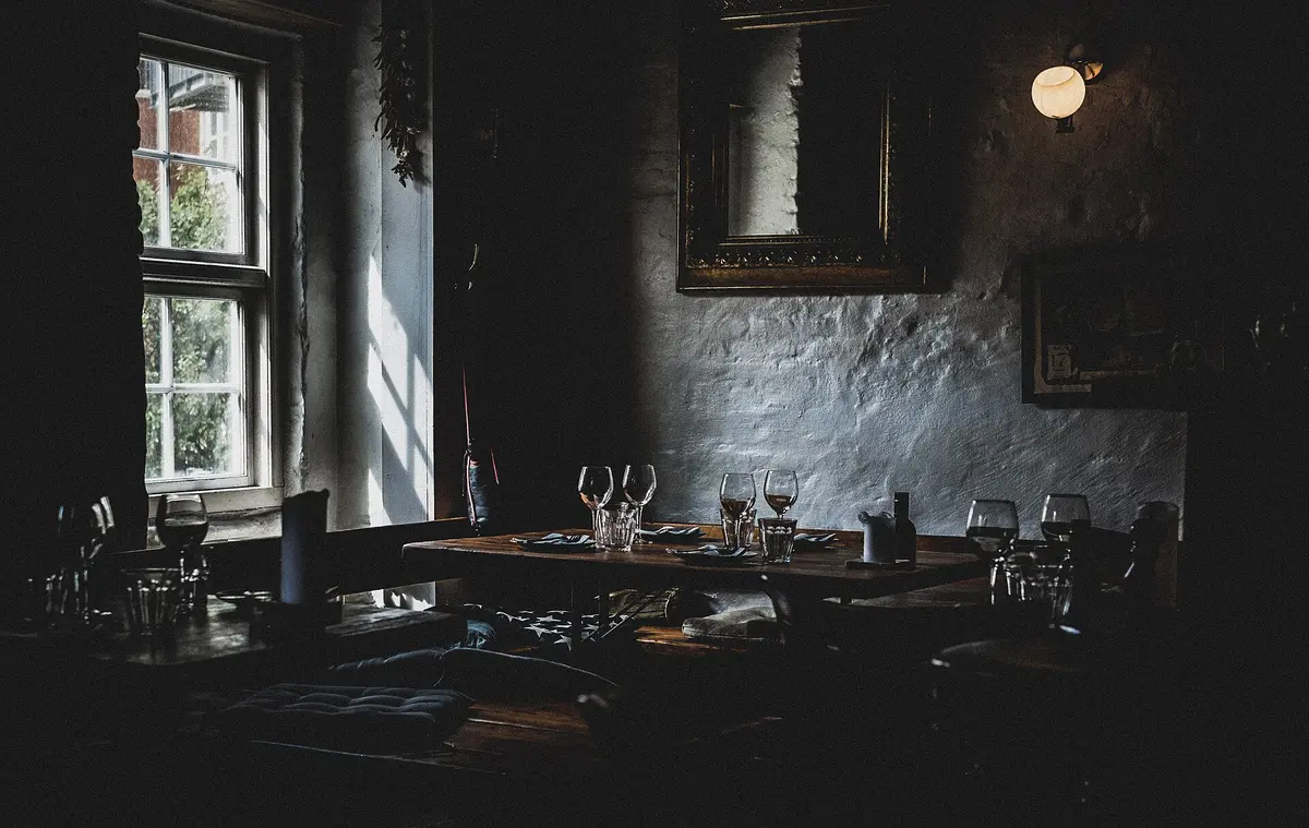 A dim, quiet dining room with tables laid