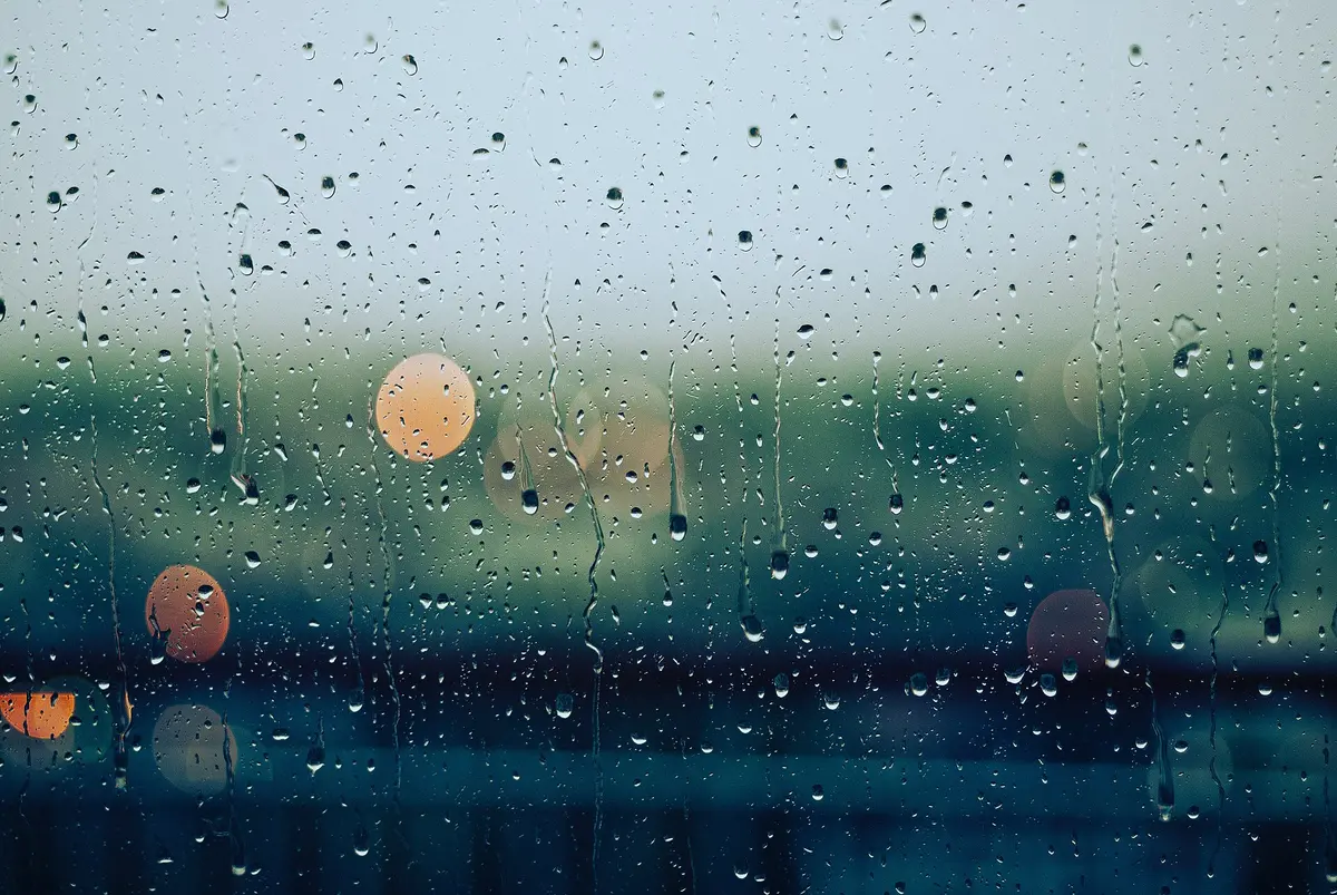 Raindrops on glass with soft lights behind