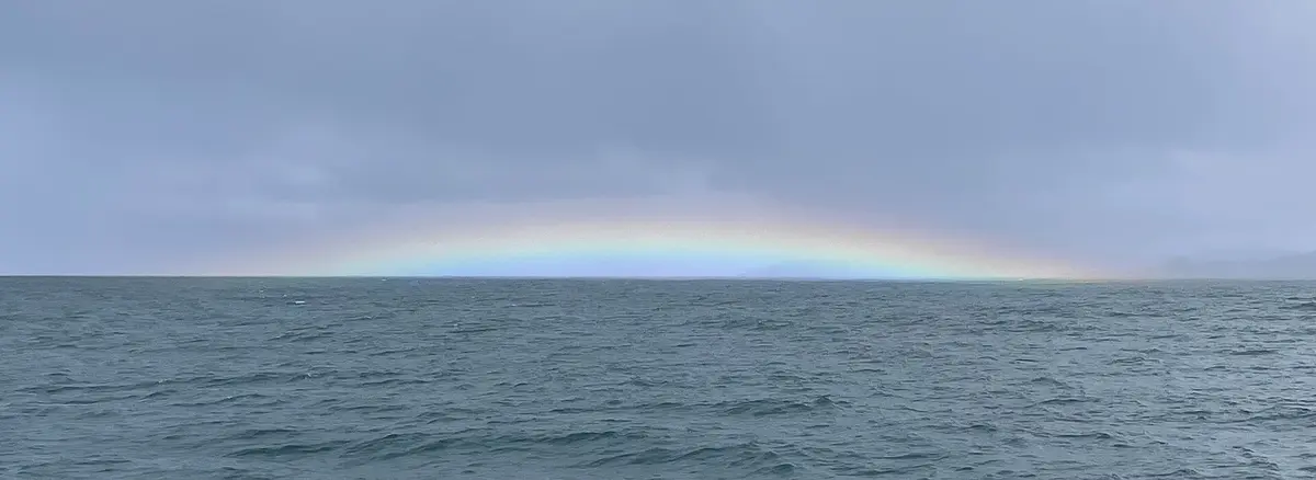 Open sea under a low rainbow